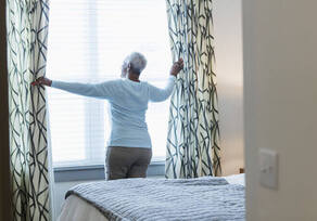 Lady opening her window. It looks as if she has just gotten out of bed.